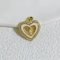 Primo piano dettagliato del ciondolo a cuore dorato con zirconi e raffinato motivo sacro. - Stile Vergine Maria a Cuore (4)