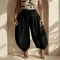 Detail shot of women's black high-waisted lantern pants featuring a stylish pleated drape design. - S / Bottoms / Black