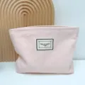 Semplice borsa cosmetica in tela rosa con cerniera ed etichetta decorativa per viaggi. - Rosa chiaro