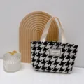 Primer plano de un bolso de lona con estampado de pata de gallo y etiqueta tejida. - Pata de gallo