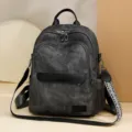 Primo piano dettagliato dello zaino in tela grigio scuro con doppie zip e tracolla fantasia. - Nero