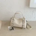 Vista dettagliata della borsa a mano cilindrica beige con fibbie, ottima fattura. - Bianco avorio