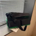 Vista dettagliata della borsa da viaggio sportiva in tela nero e verde con tasche e tracolla. - Nero