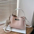 Sac seau élégant en cuir rose avec poignée supérieure et bandoulière chic et pratique. - Rose avec pendentif