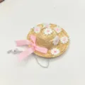 Primo piano dettagliato del cappello di paglia per animali con fiocco rosa e ricamo di fiori. - Rosa