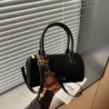 Detail van de zwarte suède cilindervormige tas met metalen hardware en bloemhanger. - Zonder Hanger / Zwart