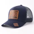 Gorra trucker azul marino con parche de cuero de león y malla transpirable para actividades. - Estilo Parche Cuero León (BQ657) / Azul marino