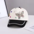 Detalle de mariposa de estrás en gorra de béisbol, con acentos brillantes y ala elegante. - Ajustable / Mariposa Colorida / Beige Negro Color Block