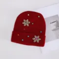Detalle de primer plano de gorro de punto rojo oscuro con flor de pedrería y cristales brillantes. - Strass de Colores Flor de Seis Pétalos / Burdeos