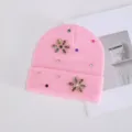 Primer plano de un gorro de invierno rosa para mujer con decoraciones de flores de estrass. - Strass de Colores Flor de Seis Pétalos / Rosa