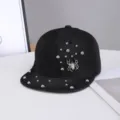 Primer plano de la gorra plana de mezclilla negra con remaches de metal y adorno de araña. - Ajustable / Motivo de Araña / Negro