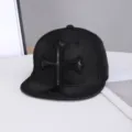 Primer plano de gorra plana de mezclilla negra con parche de cruz de cuero distintivo. - Ajustable / Motivo de Cruz de Cuero / Negro