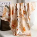 Detailed shot of a luxury silk square scarf featuring elegant abstract floral prints in orange. - H14