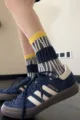 Gros plan détail de chaussettes mi-hautes rayées tendance avec revers jaunes, style urbain. - Taille unique / Bord Jaune