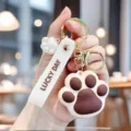 Macro view of cute brown and white silicone cat paw keychain with Lucky Day strap - Brown