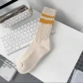 Close-up of cream crew socks featuring double yellow stripes and a soft ribbed knit texture. - Yellow Double Stripes (Beige Body)