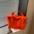Orange short-distance travel duffel bag detail, featuring durable fabric and sturdy handles. - Orange