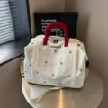 Vista detallada de la bolsa de viaje grande con lindo bordado de lazos y asas rojas. - Blanco Roto