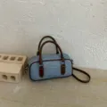 Denim pillow bag detail, blue fabric with brown leather handle, quilted texture design - Coffee