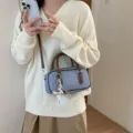 Detailed close-up view of the stylish denim Boston shoulder bag with brown leather trim. - With Pendant / Coffee With Charm