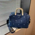 Blue travel duffel bag with white bow embroidery and sturdy handles for short business trips. - Blue