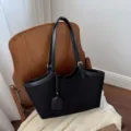 Detailed view of black suede women tote bag, minimalist shoulder handbag closeup in home setting. - Black