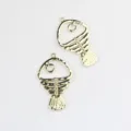 Detail shot of gold alloy hollow fish skeleton pendant charms for DIY jewelry making crafts. - Gold