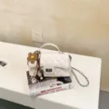 Λευκή καπιτονέ γυναικεία τσάντα ώμου με αλυσιδωτό λουράκι και λουλουδάτο μενταγιόν. - Λευκό με μενταγιόν