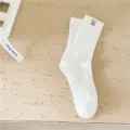 Solid white cotton mid-tube socks with textured ribbed design and mini woven label for men. - One Size / White