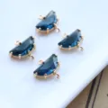 Detail shot of half-circle dark blue crystal pendants with gold plated bezels and dual loops. - Ink Blue