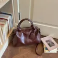 Gedetailleerd overzicht van een vintage donkerbruine boston schoudertas met dubbele handgrepen. - Eén maat / Bruin