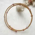 Close-up detail view of the multi-layer gold wire bracelet adorned with pink pearls. - Purple Gold Style