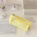 Close-up view of a stylish yellow ruffled pencil case with transparent window and zipper. - Yellow
