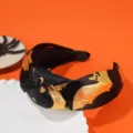 Close-up detail of Halloween knotted headband with gold bat pattern on black satin fabric - Gold Bat Style / Black and Gold