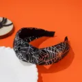 Detailed view of a Halloween wide-brimmed knotted headband with silver spider web pattern. - Silver Spider Web / Black and Silver