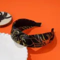 Detailed view of Halloween knotted headband with gold spider web pattern on black satin - Gold Spider Web Style