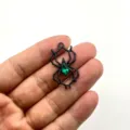 Nahaufnahme des schwarzen Metallspinnenanhängers mit grünem Kristall für DIY-Schmuck. - Schwarze Spinne Grüner Strass