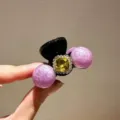 Detail shot of the sparkling rhinestone cherry hair claw clip, ideal for chic daily styles. - Purple
