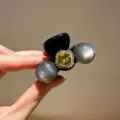 Detail shot of the elegant rhinestone hair claw clip with yellow crystal and grey pearl decor. - Gray