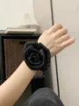 Close-up of a black satin rose hair scrunchie worn on wrist, elegant floral fabric design. - Rose Flower Scrunchie / Black