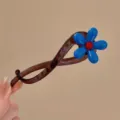 Detailed close-up of a sweet blue flower hair clip with a chic brown twisted design. - Blue Flower Twist Clip