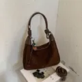 Vue détaillée du sac porté épaule marron en suédine avec texture et joli petit pendentif. - Avec Pendentif / Café