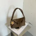 Vue détaillée du sac à épaule marron chic en suédine avec un joli pendentif floral charmant. - Avec Charme / Vert