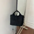 Vista detallada del bolso tote de cuero trenzado negro colgado en un perchero, textura. - Negro