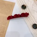Λεπτομερής κοντινή λήψη του σκούρου κόκκινου βελούδινου κλιπ μαλλιών με εξαιρετική υφή. - Πλαϊνά κλιπ / Κόκκινο