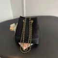 Detailed view of the black quilted suede bucket bag featuring metallic chain straps. - With Pendant / Black