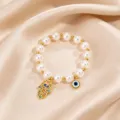 Closeup view of the gold stainless steel Hamsa hand and eye pearl bracelet details. - Hamsa Hand Pearl Style