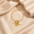 Close-up detail of the 18K gold-plated butterfly and pearl charm bracelet on satin. - Bowknot Artificial Pearl Bracelet