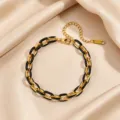 Nahaufnahme der Textur des schwarz-goldenen Edelstahl-Kubanerketten-Modearmbands. - Schwarzes Emaille-Armband