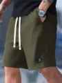 Detail view of men's casual waffle knit shorts with white drawstrings and logo patch. - Army Green